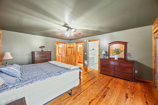 bedroom featuring a ceiling fan, baseboards, ensuite bath, and wood finished floors