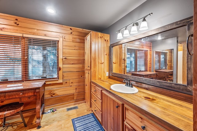 bathroom with wooden walls, visible vents, vanity, and wood finished floors