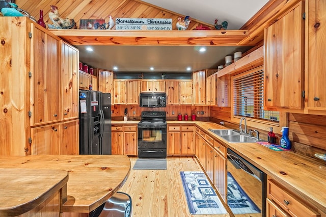 kitchen featuring a sink, wood counters, vaulted ceiling, light wood-type flooring, and black appliances