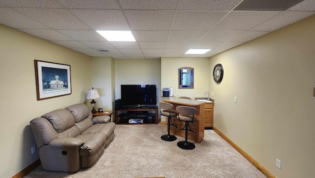 carpeted living area with a paneled ceiling and baseboards