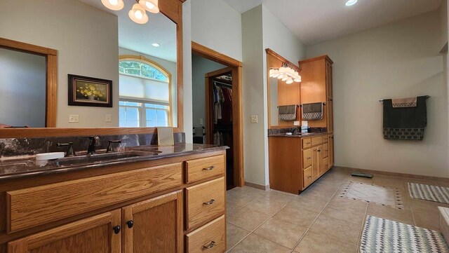 bathroom featuring tile patterned flooring, a walk in closet, vanity, and baseboards