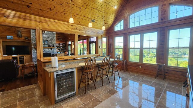 bar featuring beverage cooler, wood ceiling, a bar, wood walls, and high vaulted ceiling