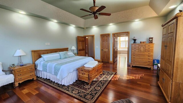 bedroom with baseboards, dark wood finished floors, a ceiling fan, and ensuite bathroom