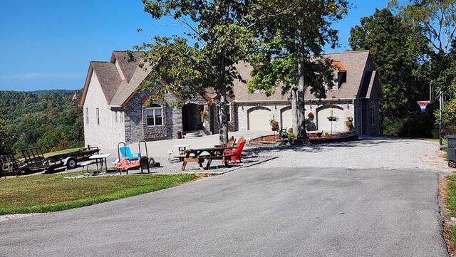 view of front of house with a garage, a front yard, and gravel driveway