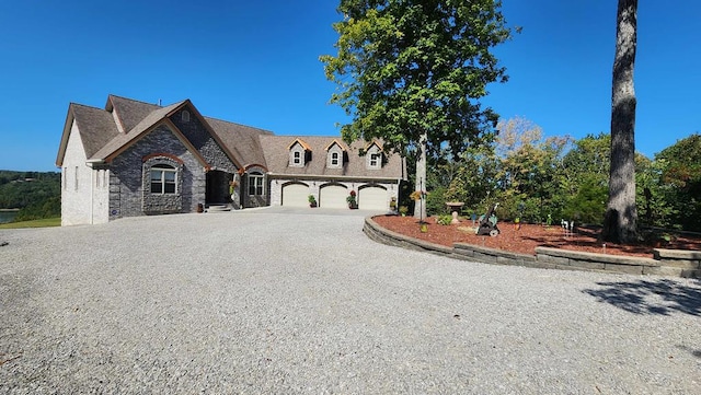 view of front of property featuring a garage, stone siding, and driveway