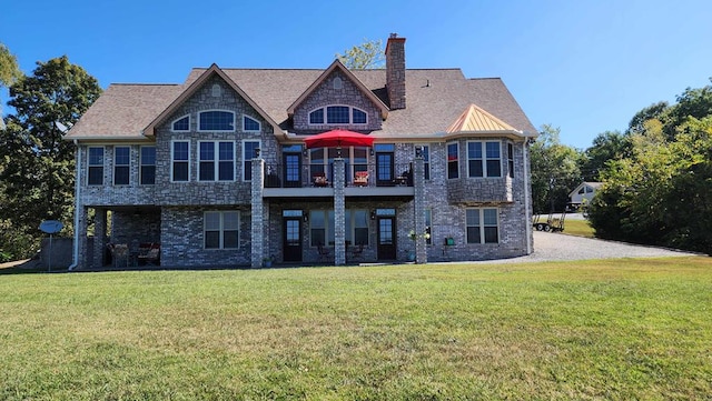 back of property with stone siding, brick siding, a lawn, and a chimney