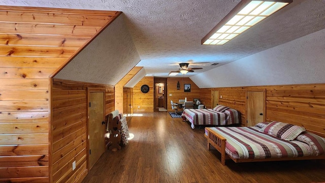 bedroom featuring wooden walls, vaulted ceiling, a textured ceiling, and wood finished floors