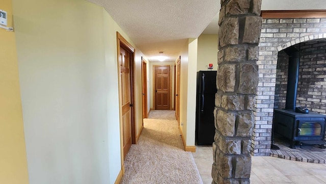 hallway featuring a textured ceiling, light carpet, and baseboards