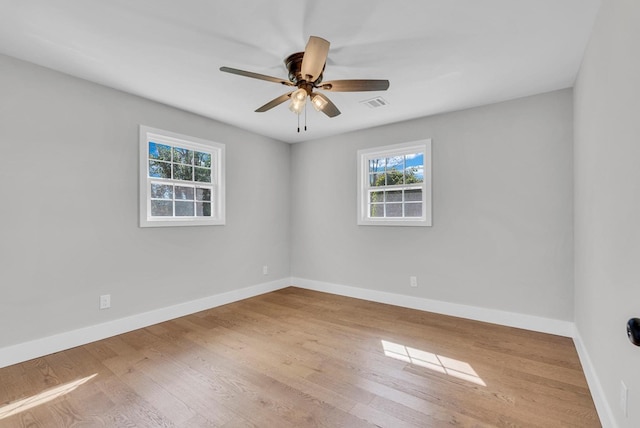 spare room featuring visible vents, ceiling fan, baseboards, and wood finished floors