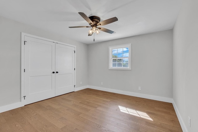 unfurnished bedroom featuring light wood-style flooring, baseboards, ceiling fan, and a closet