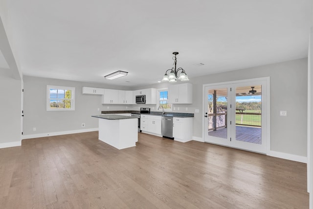 kitchen featuring a kitchen island, white cabinets, hanging light fixtures, appliances with stainless steel finishes, and dark countertops