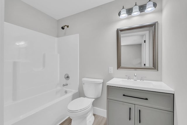 bathroom featuring baseboards, toilet, wood finished floors,  shower combination, and vanity