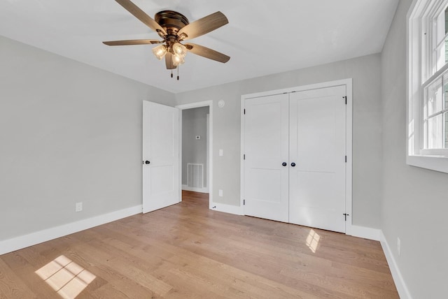 unfurnished bedroom featuring a closet, visible vents, ceiling fan, light wood-type flooring, and baseboards