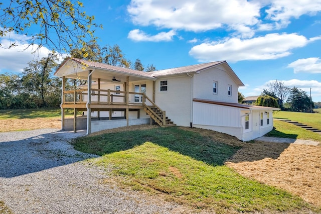 back of property featuring gravel driveway, brick siding, a lawn, stairway, and metal roof