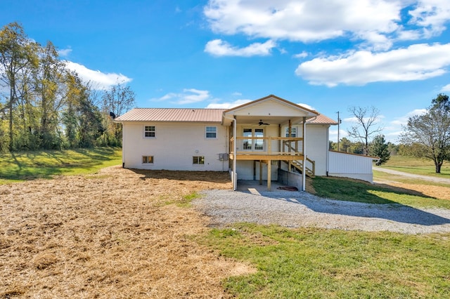 back of property with a ceiling fan, metal roof, a wooden deck, and a lawn