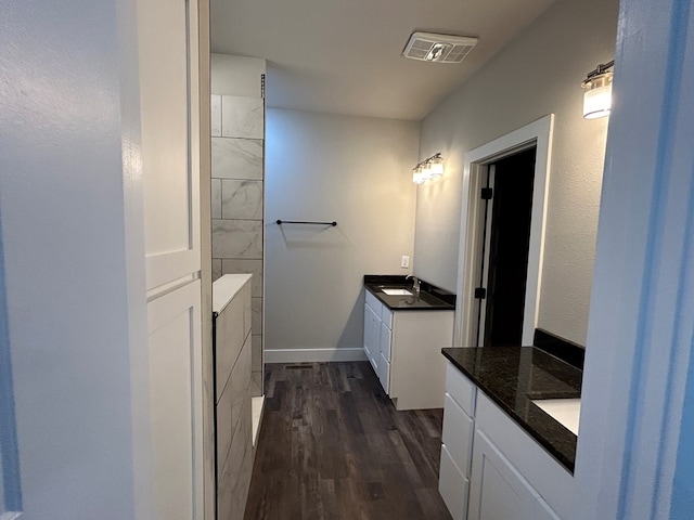 bathroom featuring two vanities, visible vents, a sink, wood finished floors, and baseboards