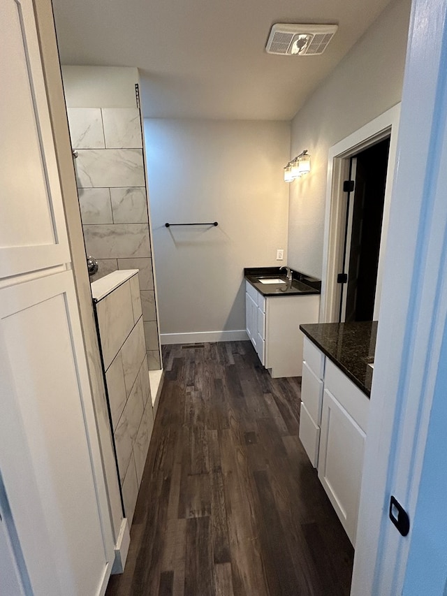 bathroom with two vanities, visible vents, a sink, wood finished floors, and walk in shower