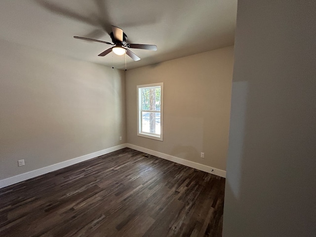 spare room featuring dark wood-style floors, ceiling fan, and baseboards