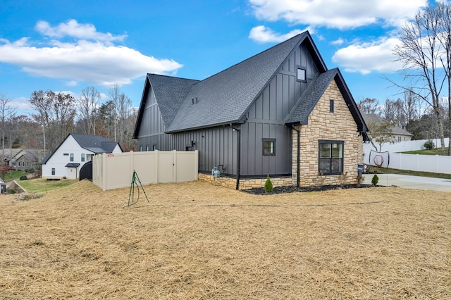 view of home's exterior with a shingled roof, fence, and board and batten siding