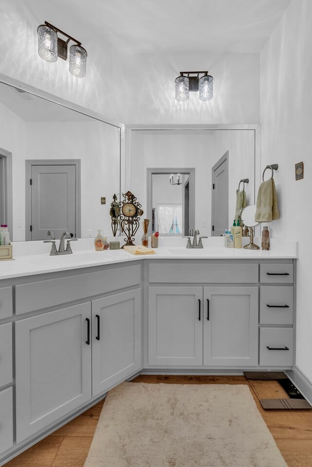 full bath featuring double vanity, a sink, and wood finished floors