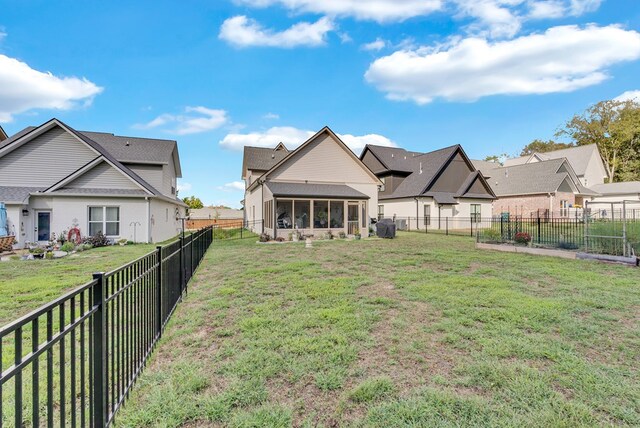 rear view of property with a residential view, a sunroom, a fenced backyard, and a yard