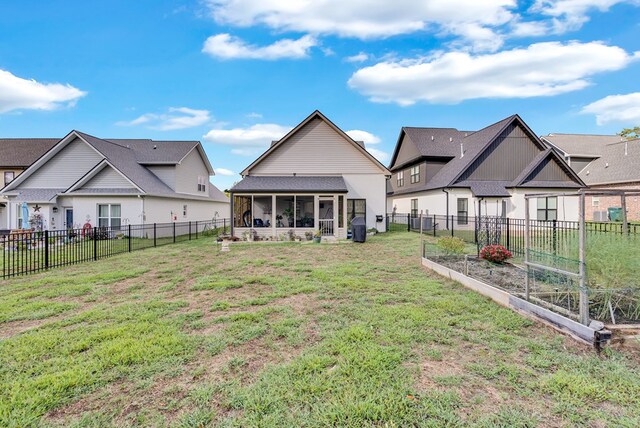 rear view of property with a garden, a yard, a fenced backyard, and a sunroom