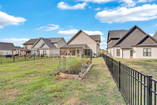 view of yard featuring a residential view, a garden, and a fenced backyard