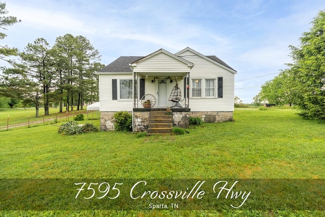 bungalow-style home with roof with shingles, fence, and a front lawn