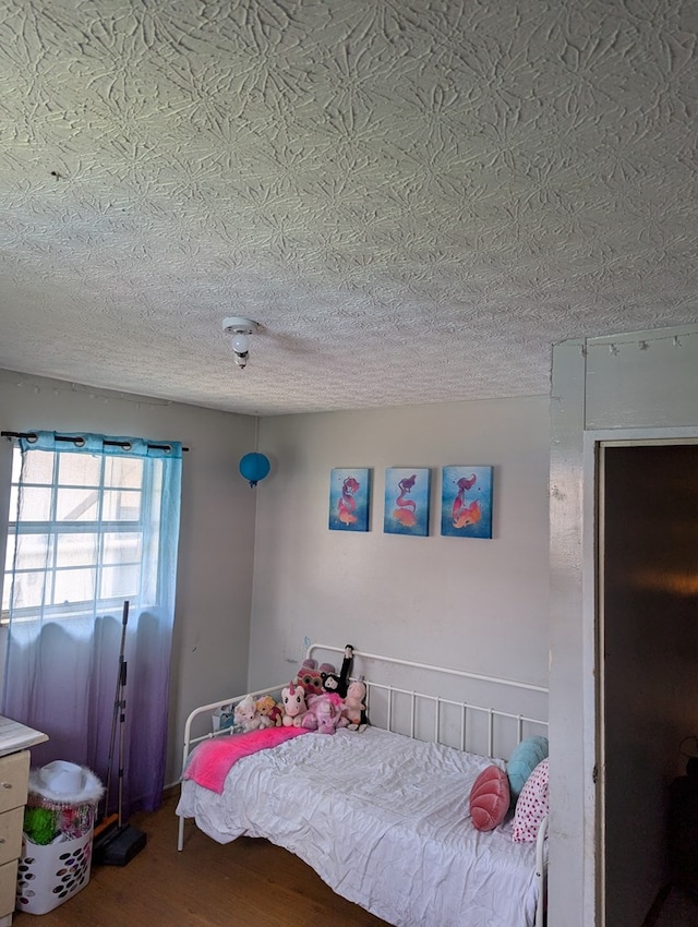 bedroom featuring ceiling fan, a textured ceiling, and wood finished floors