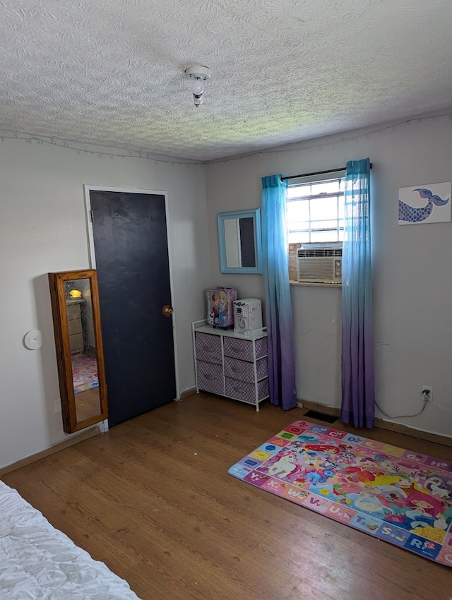 bedroom featuring a textured ceiling, cooling unit, and wood finished floors