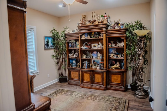 living area featuring light wood-type flooring, ceiling fan, and baseboards