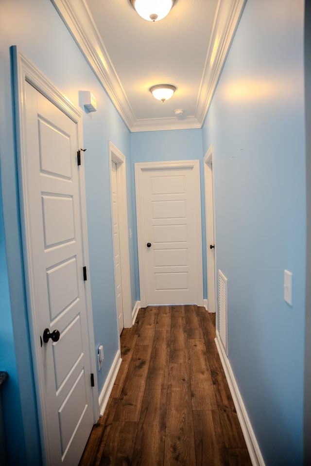 hall with baseboards, visible vents, ornamental molding, and dark wood-type flooring