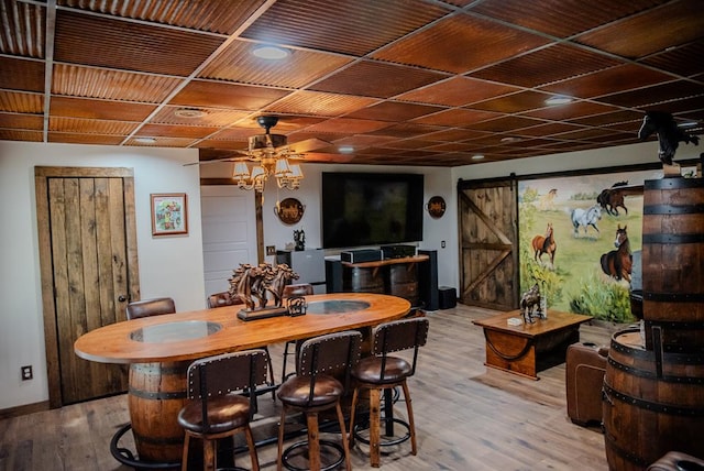 dining area with a barn door, baseboards, a ceiling fan, wooden ceiling, and light wood-style floors