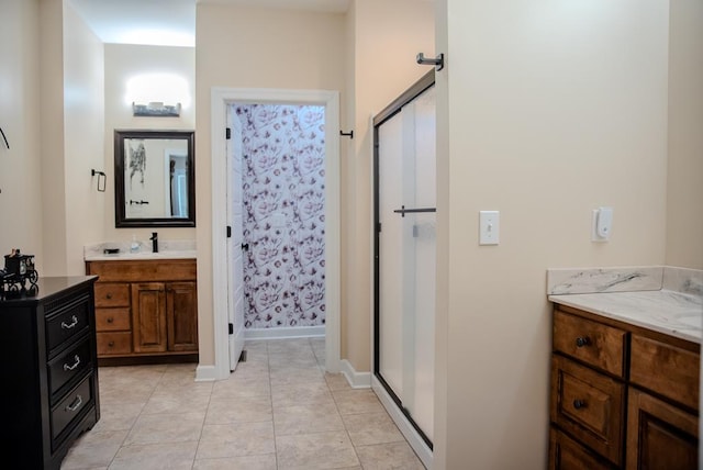 full bathroom with a stall shower, tile patterned floors, baseboards, and vanity