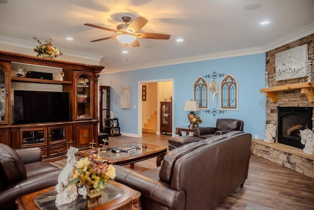 living room featuring a ceiling fan, a fireplace, light wood-style flooring, and ornamental molding