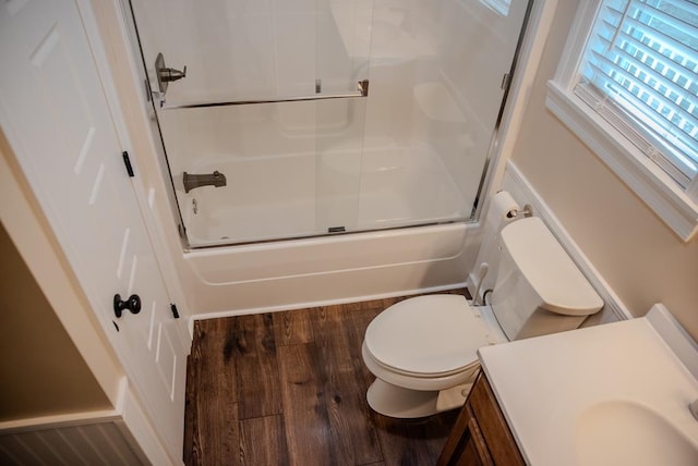 bathroom with toilet, enclosed tub / shower combo, wood finished floors, and vanity