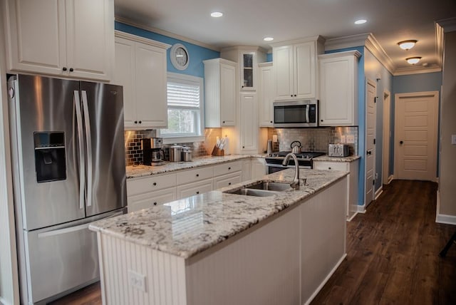 kitchen with white cabinets, a kitchen island with sink, glass insert cabinets, and stainless steel appliances