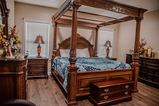 bedroom with ornate columns and wood finished floors