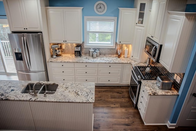 kitchen featuring white cabinets, light stone countertops, glass insert cabinets, and stainless steel appliances