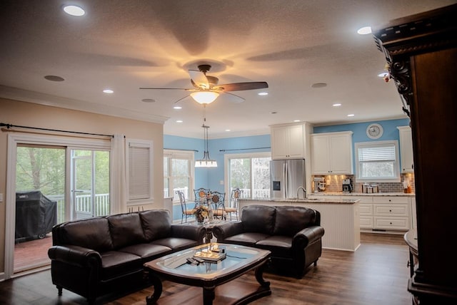 living area featuring recessed lighting, plenty of natural light, dark wood finished floors, and crown molding