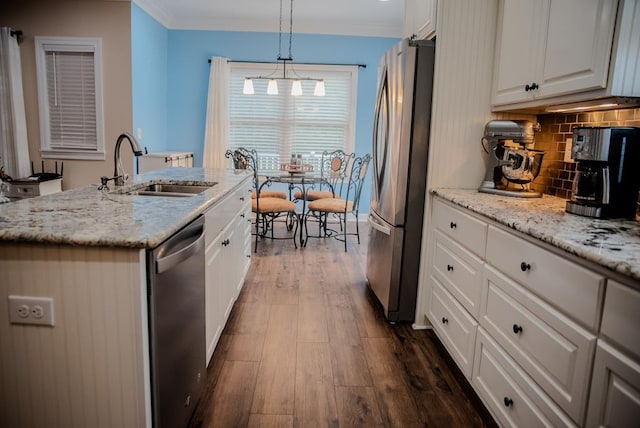 kitchen featuring white cabinets, an island with sink, hanging light fixtures, stainless steel appliances, and a sink