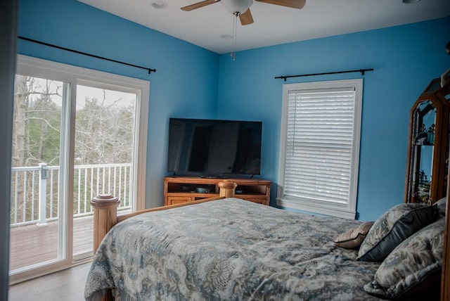 bedroom featuring access to outside, multiple windows, ceiling fan, and wood finished floors