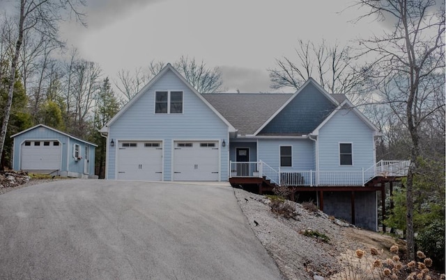 view of front of home featuring a shingled roof, an outbuilding, and driveway