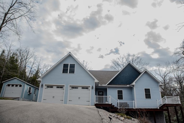 view of front of property with a garage, aphalt driveway, roof with shingles, and an outdoor structure