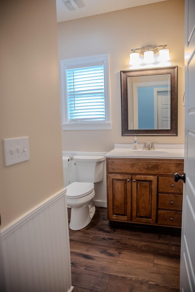 bathroom with toilet, wainscoting, wood finished floors, and vanity