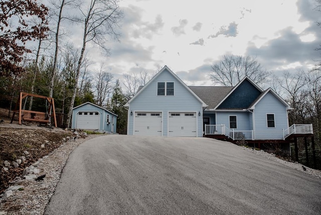 view of front of home with roof with shingles, aphalt driveway, and an outbuilding