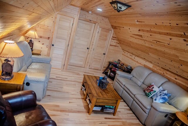 unfurnished living room featuring wooden ceiling, wood walls, vaulted ceiling, and light wood-style floors