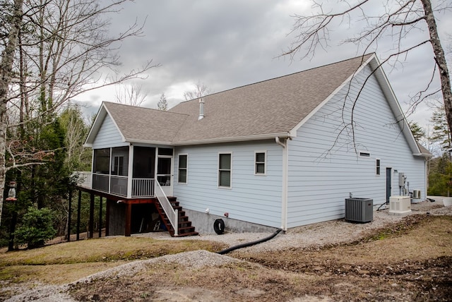 back of house featuring central air condition unit, a sunroom, stairs, and roof with shingles