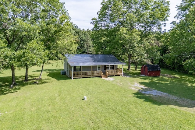 exterior space featuring driveway, metal roof, a storage unit, a deck, and a yard