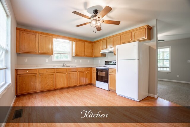 kitchen featuring white appliances, visible vents, brown cabinetry, light countertops, and under cabinet range hood